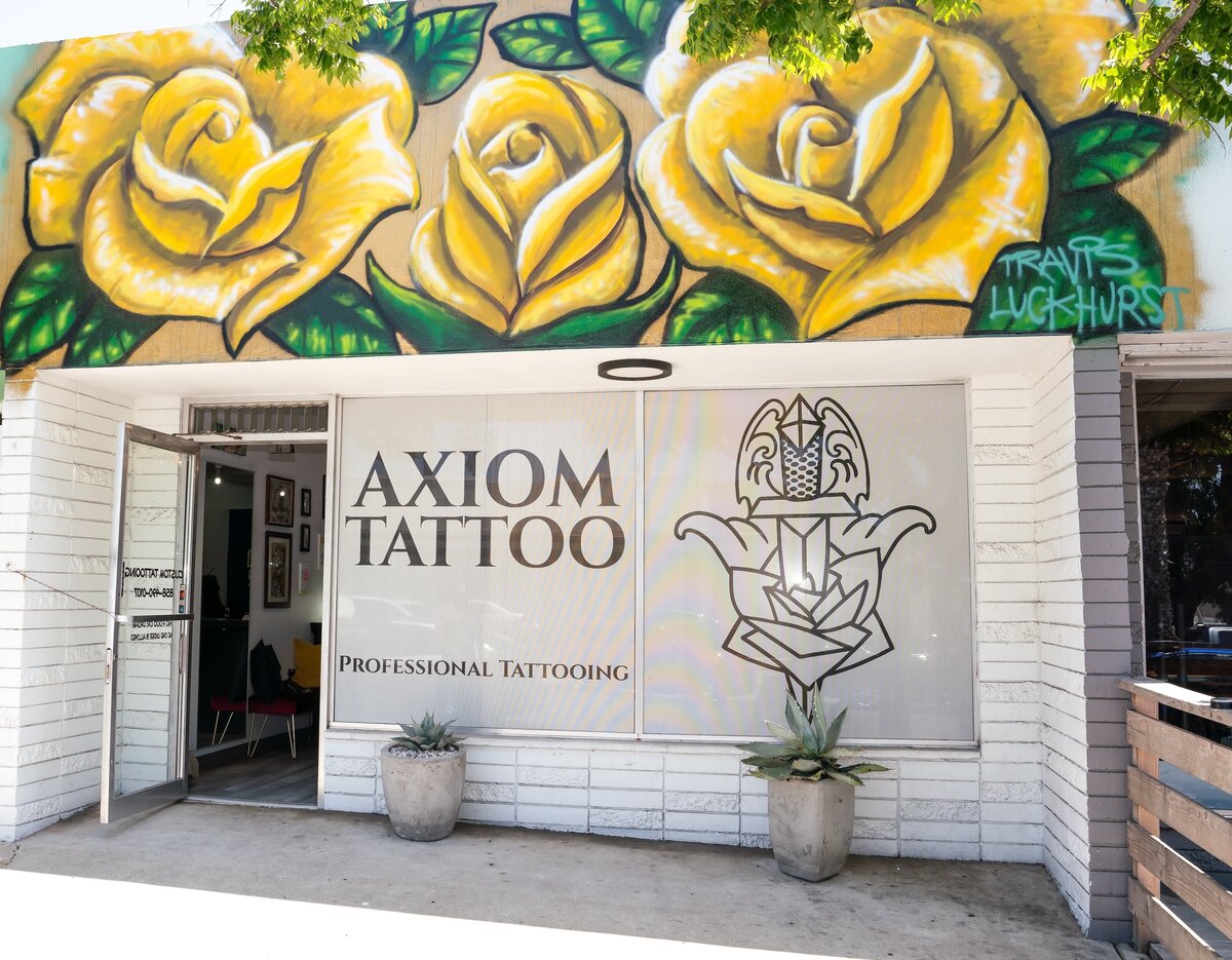 Axiom Tattoo team of tattoo artists smiling and sitting on gold and red velvet sofa