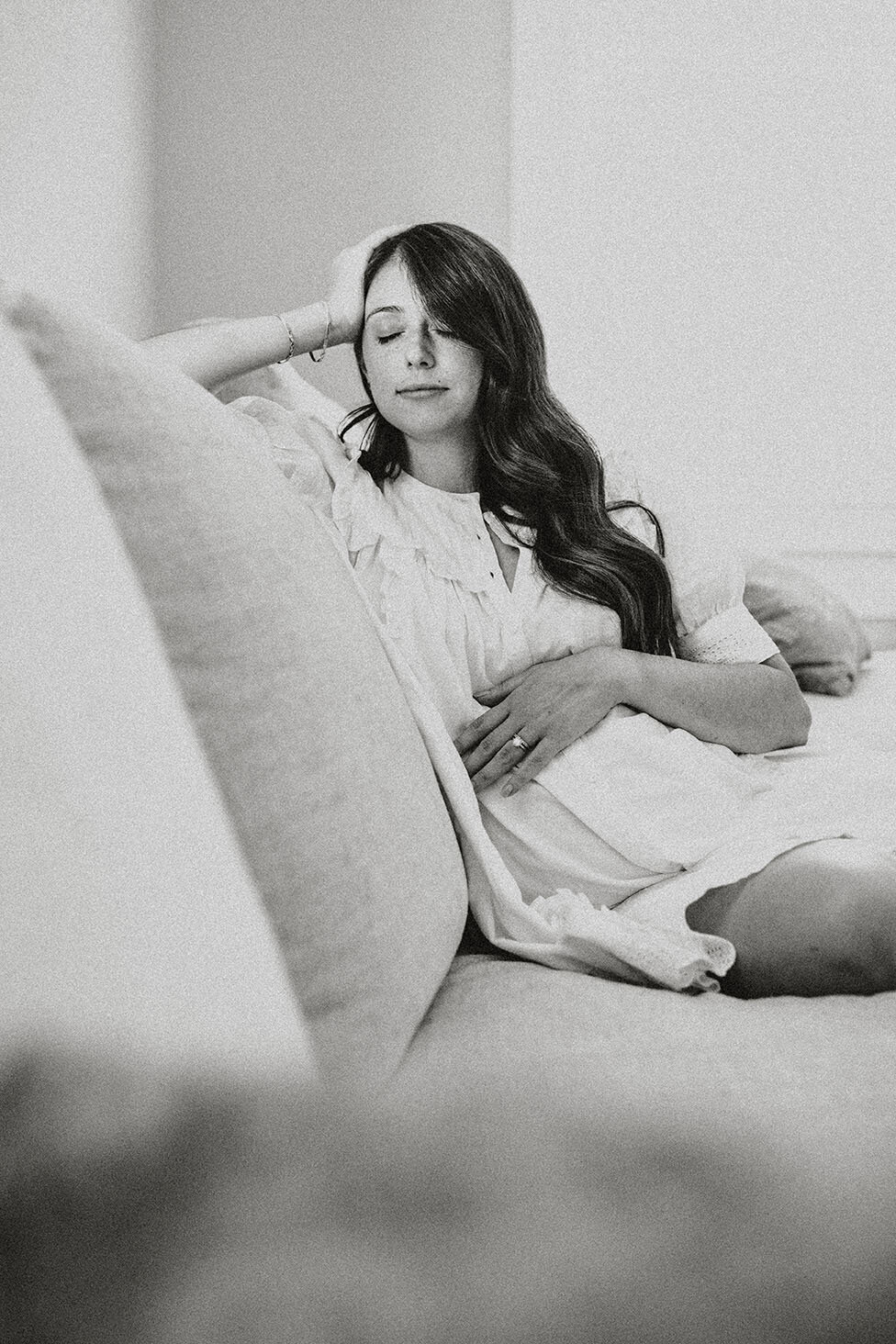 Black and white maternity portrait of a pregnant woman sitting on a couch, photographed by San Antonio family photographer Sara James.