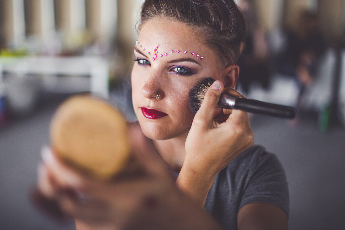 A woman applying elate cosmetics blush.