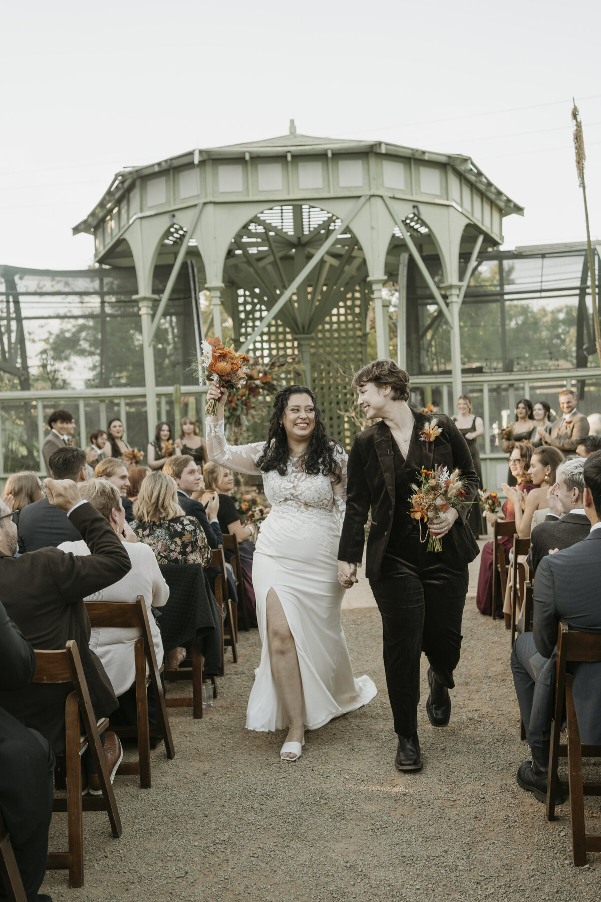 Brides couple leaving their ceremony as their guests cheer for them