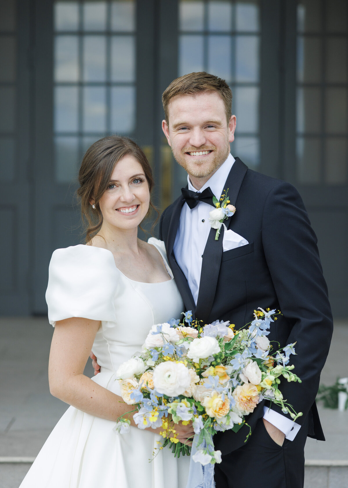 Close up of a bride and groom, the bride holding a pastel colored bouquet