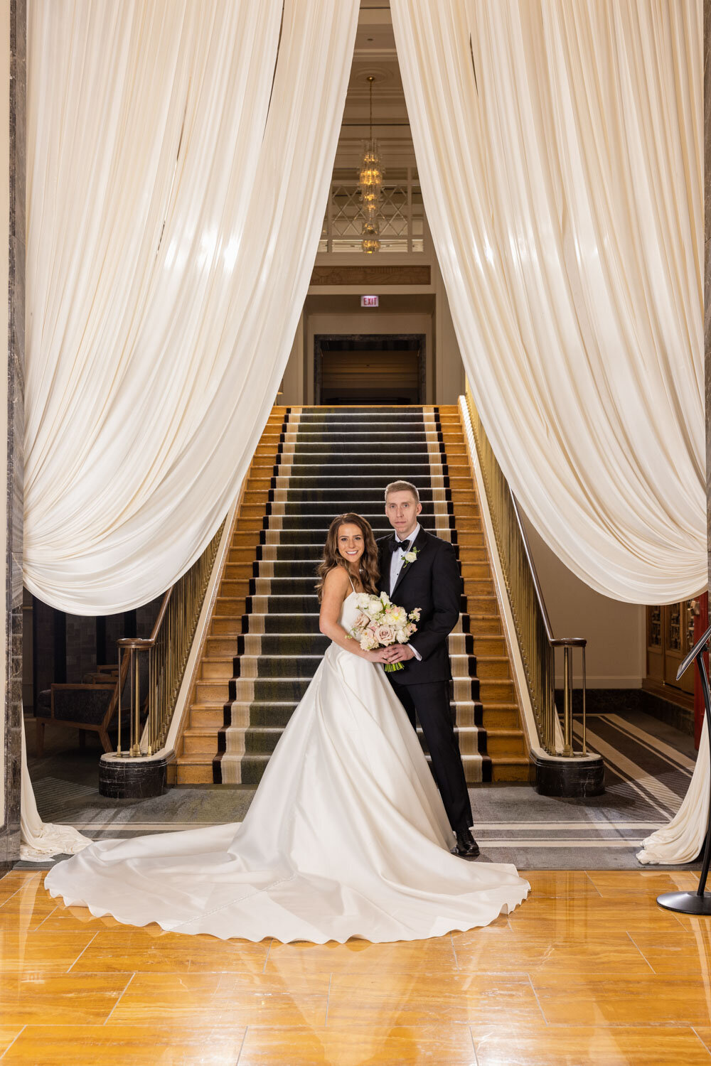 A bride and groom pose in front of a set of stairs