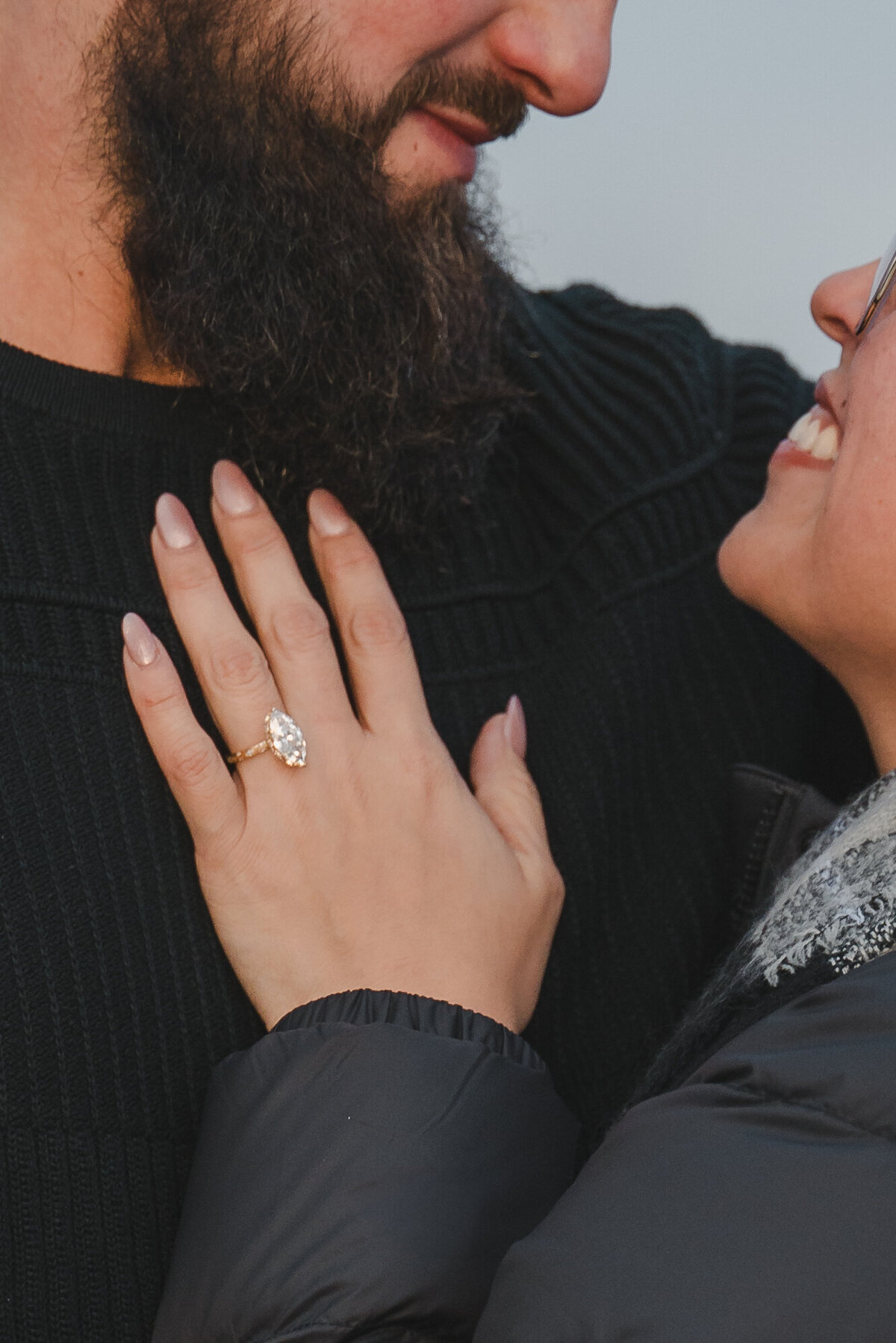 Engagement ring displayed proudly on woman's hand resting on fiancé’s chest.