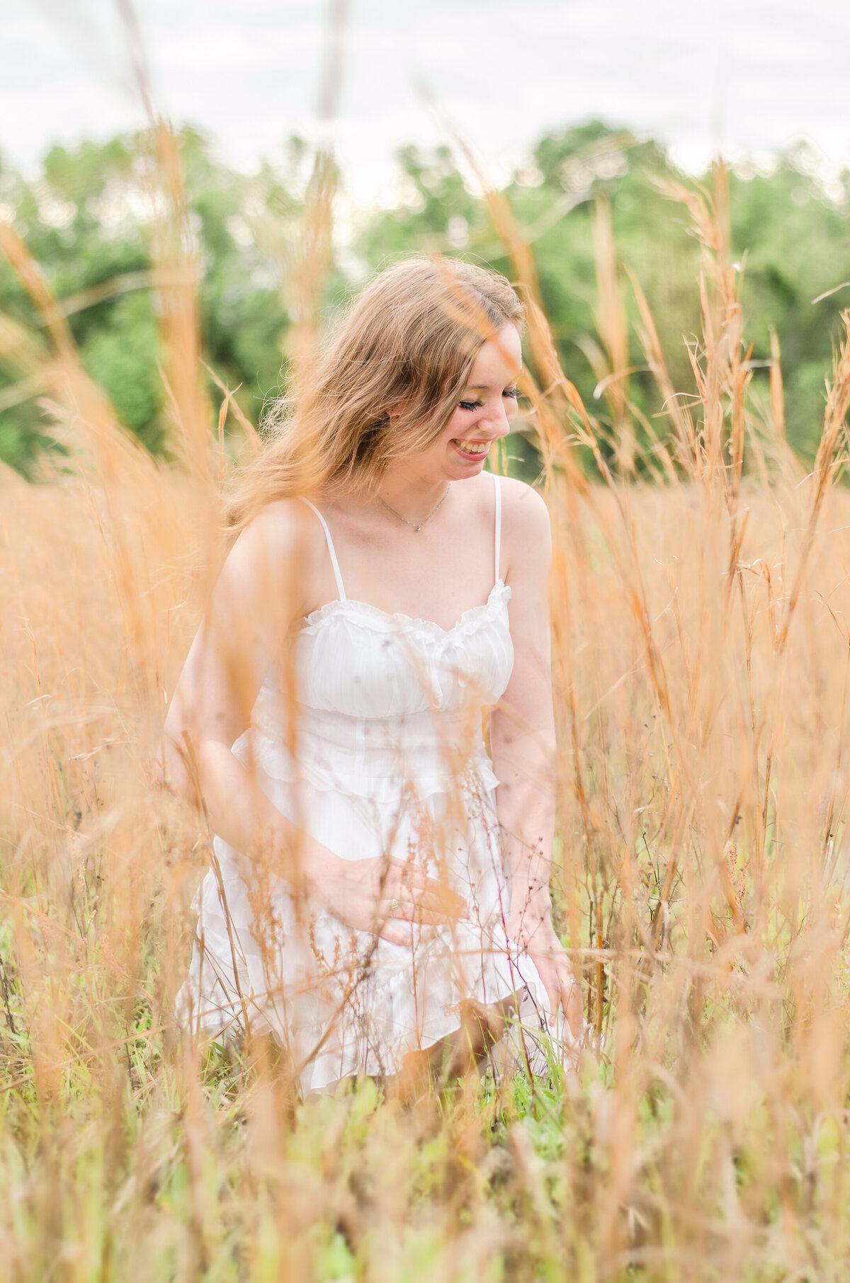 woman in a white dress laughs in a wheat field