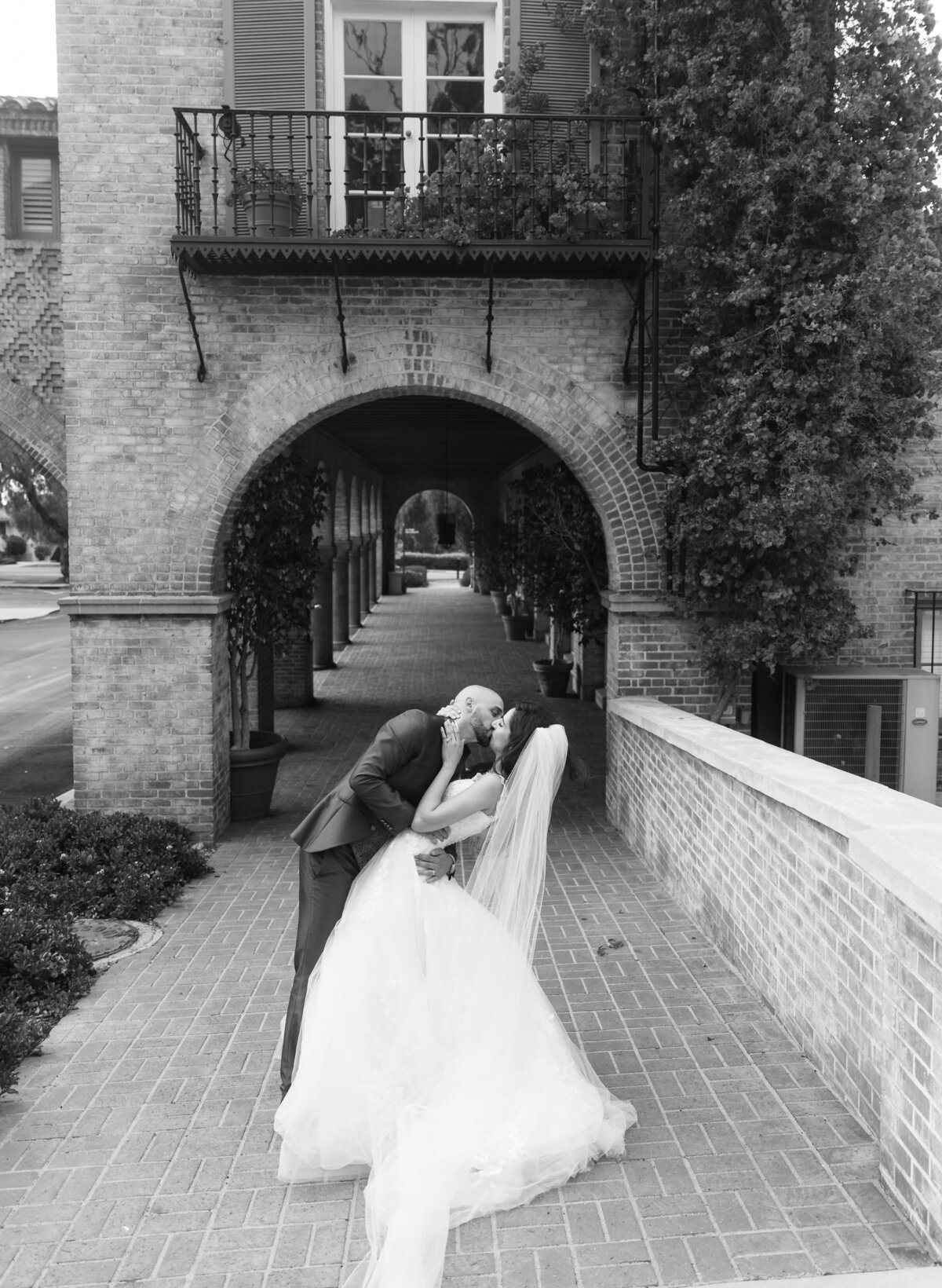 bride and groom kissing under an archway
