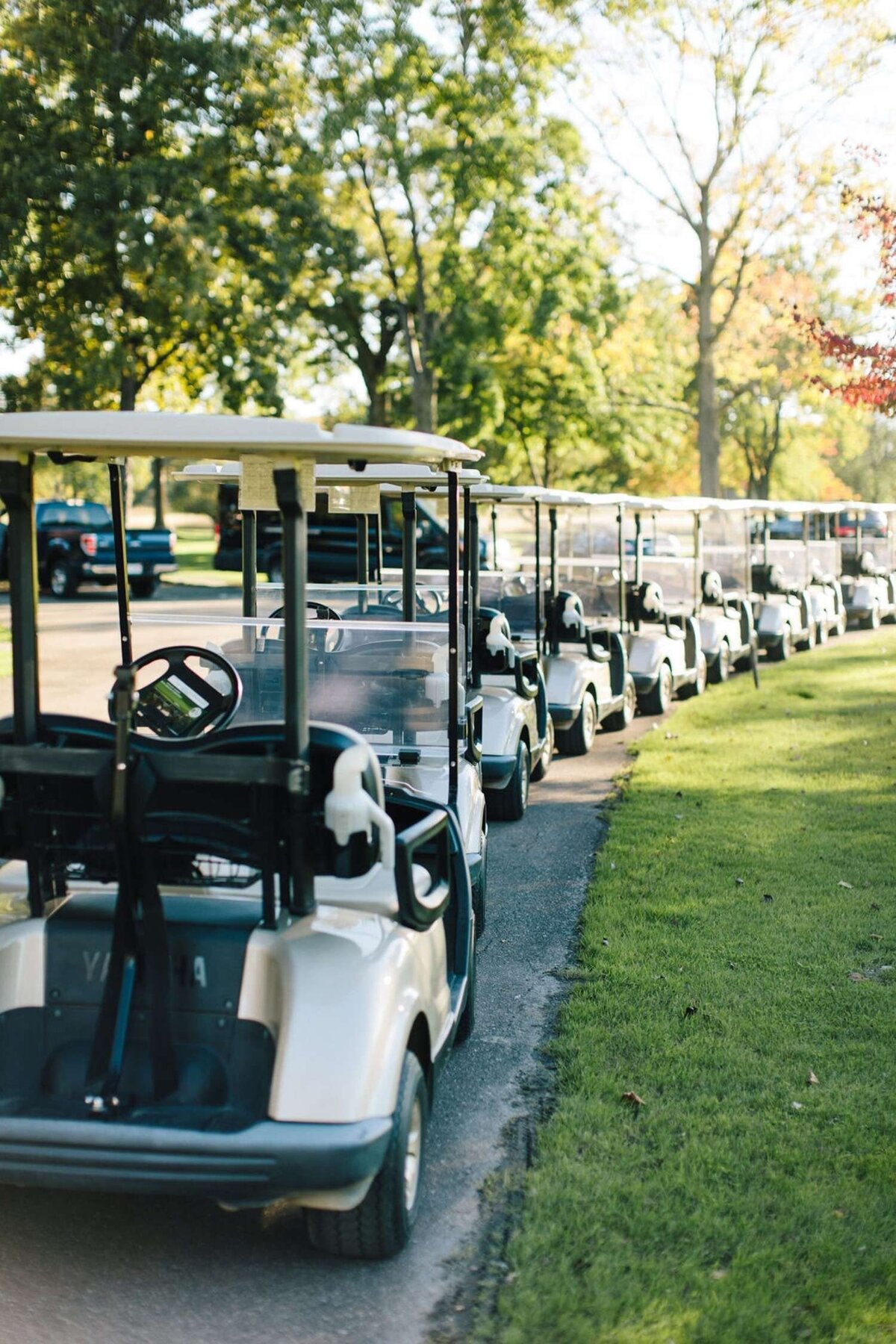 Guest Golf Carts line up along the Green at a Luxury Michigan Lakefront Golf Club Wedding.