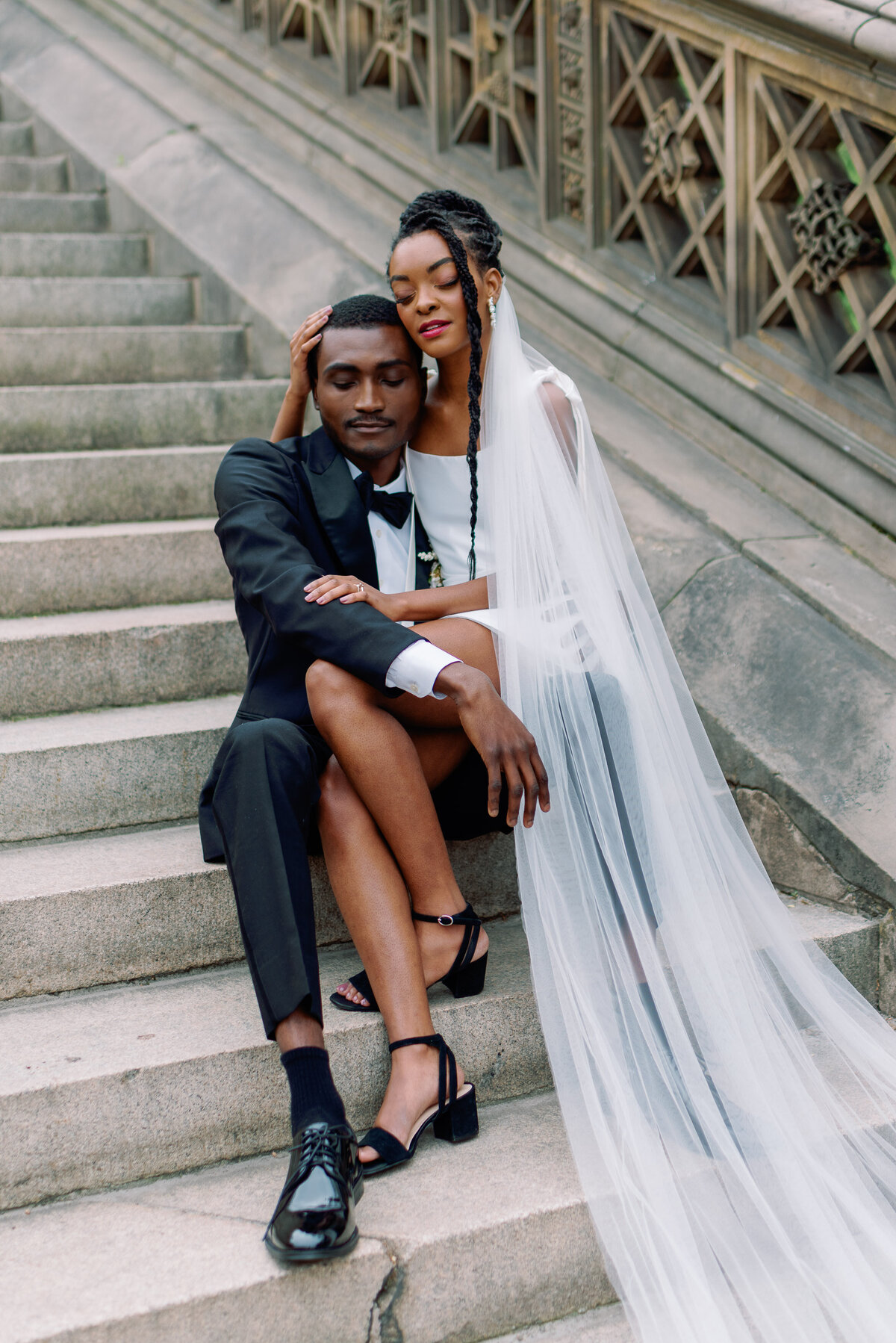 bride and groom embrace on bethesda terrance NYC steps with long veil