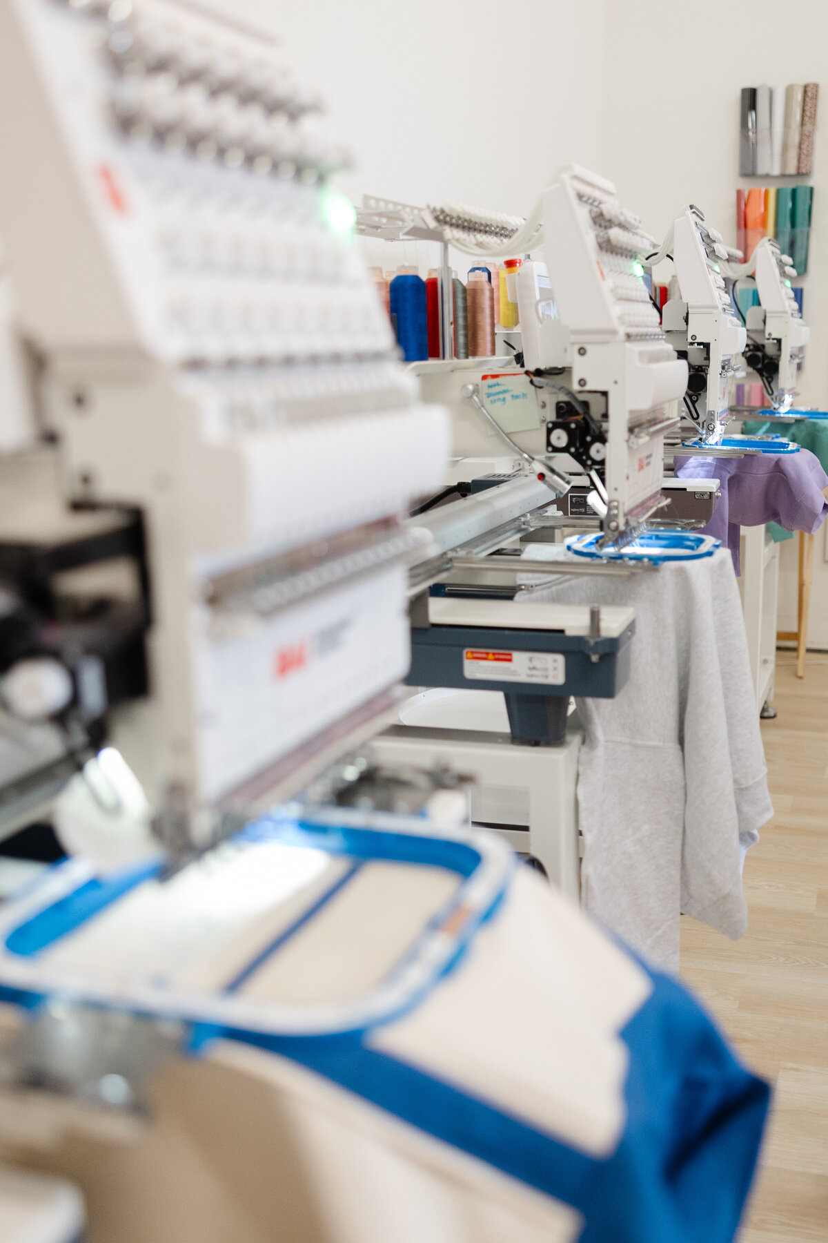 Close-up of embroidery machine stitching a design on blue fabric. Photograph by Yucaipa branding photographer Kaitlyn Dawn Photography.