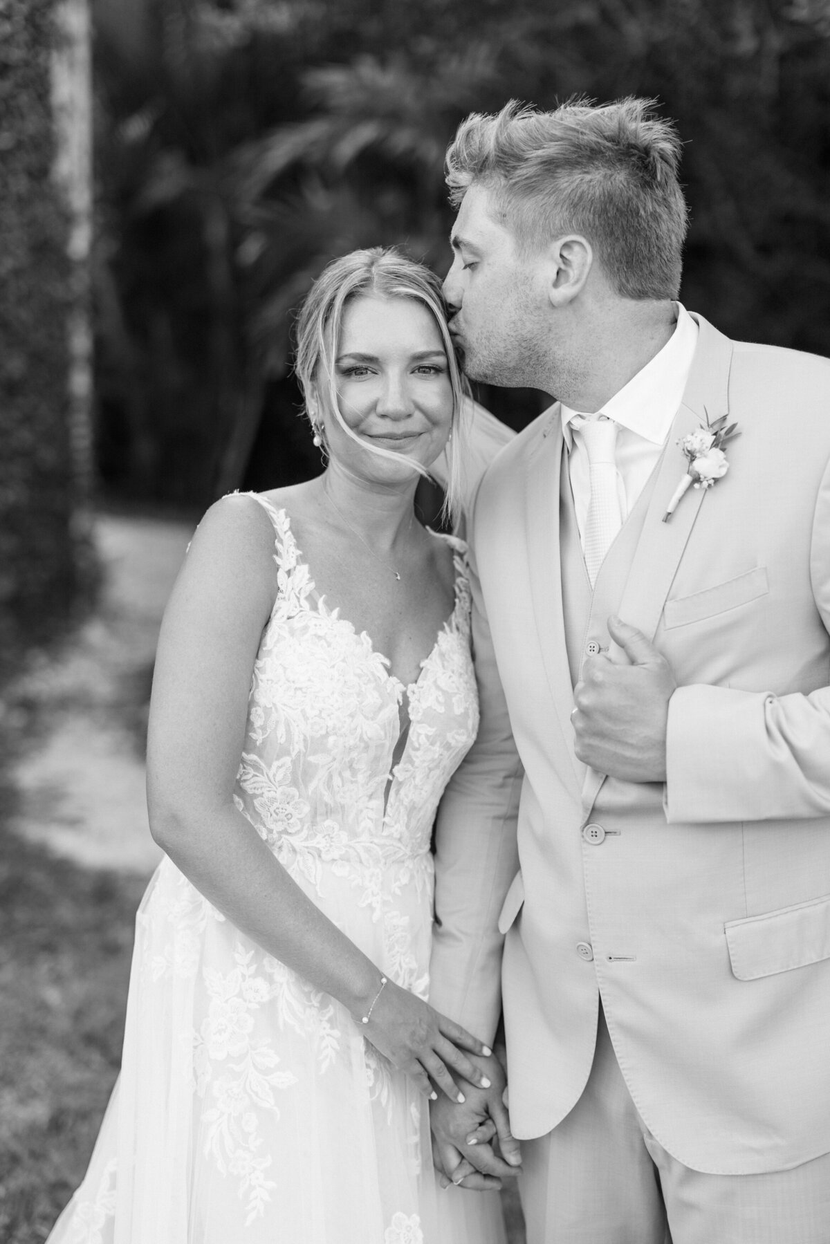 Groom kisses bride's forehead in sweet black-and-white moment at their Cancun destination wedding.