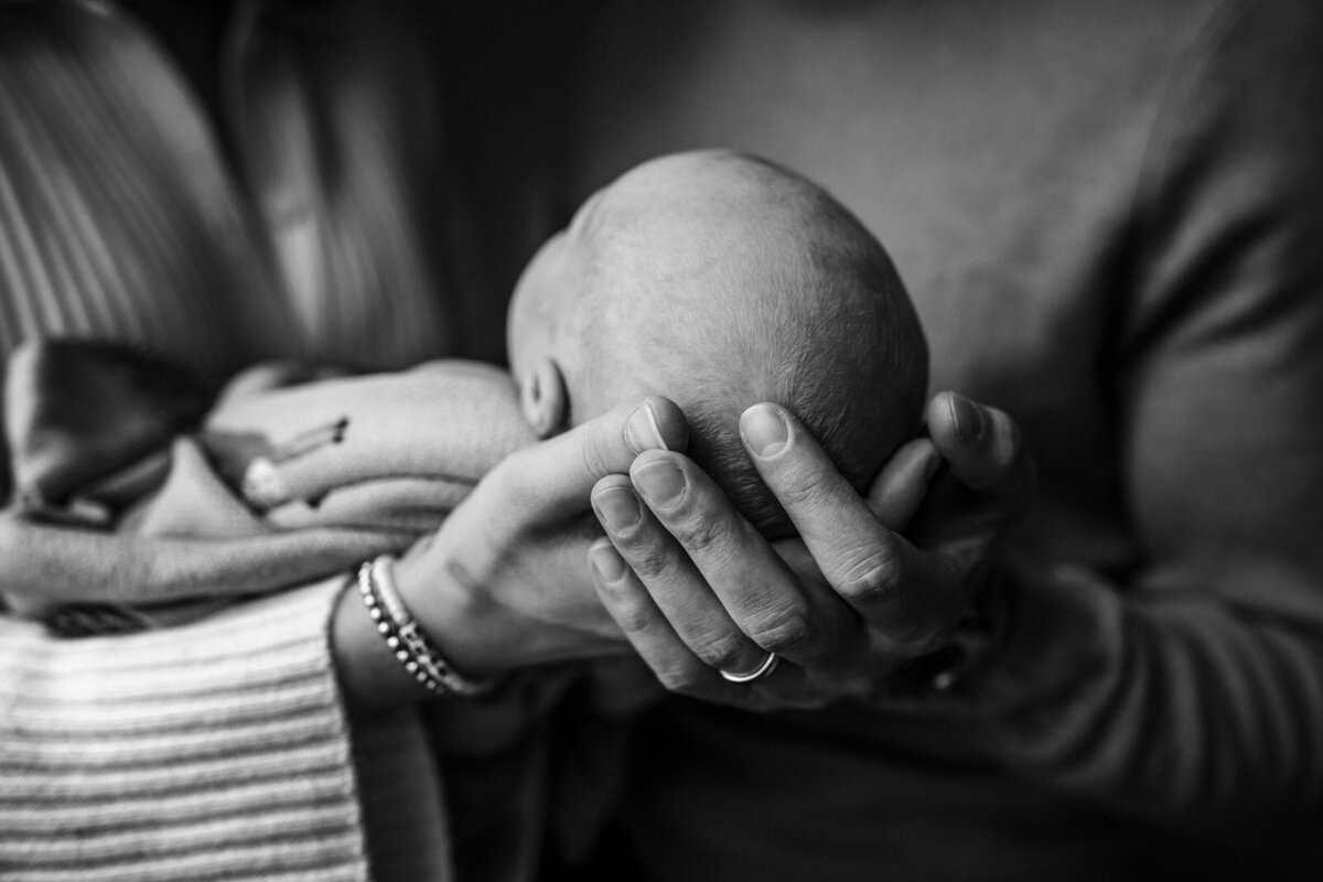 back of baby's head held by mom and dad