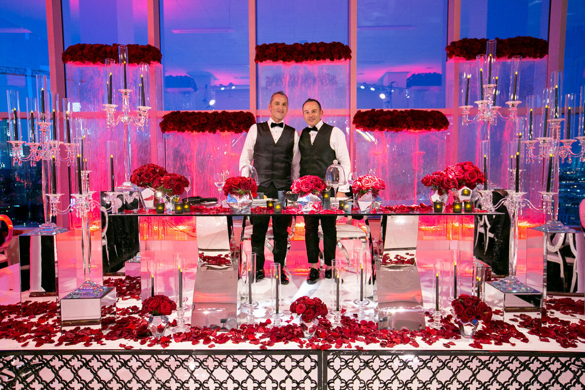 Two grooms standing behind a luxuriously decorated reception table