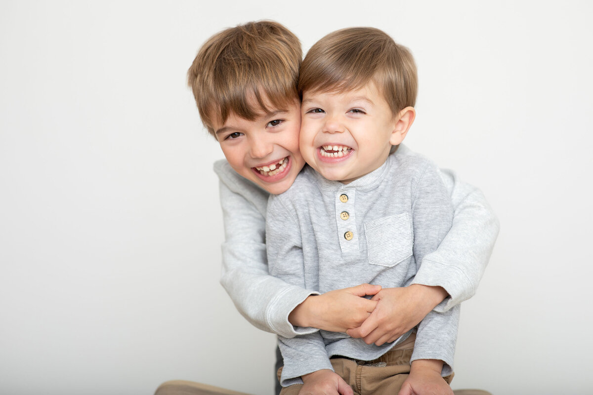 Two young brothers hugging and laughing together during a Bucks County family photography session