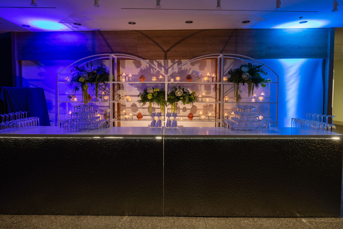 Modern bar setup with backlit shelving and floral arrangements