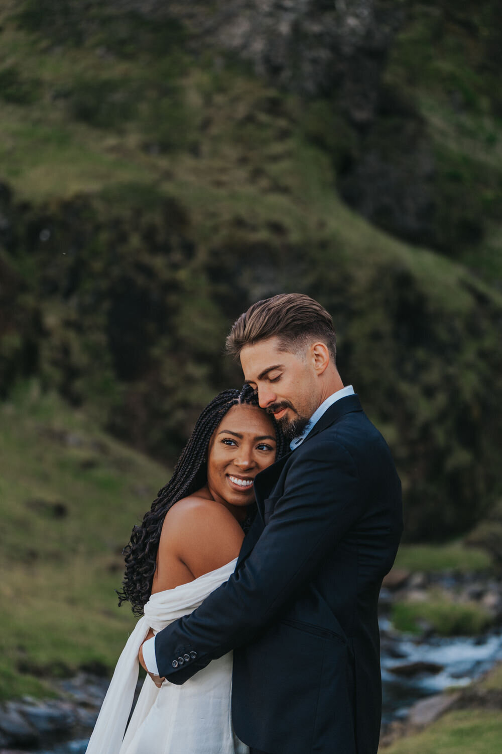 Husband holds his wife while she smiles widely 
