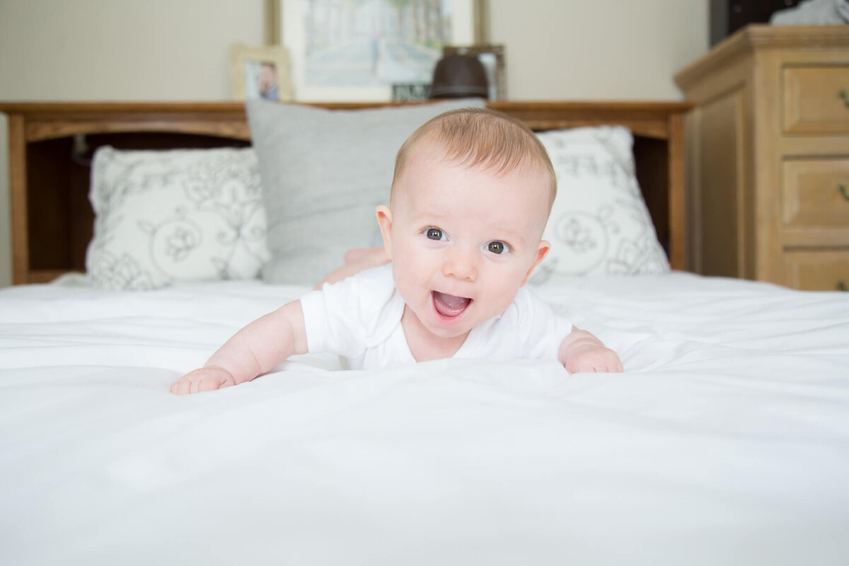 joyful baby boy excitedly smiling from tummy time on a bed