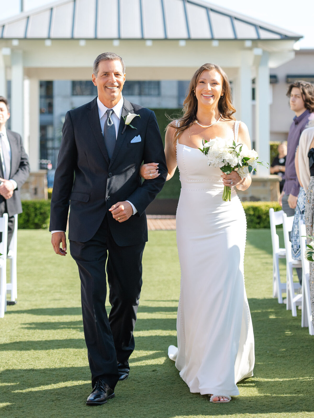 Bride walks down the aisle with her father at an outdoor wedding at Lido House