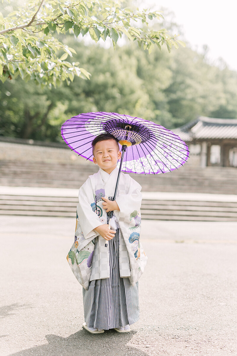 七五三の袴を着た5歳の男の子が紫色の傘を持ってポーズしている七五三写真
