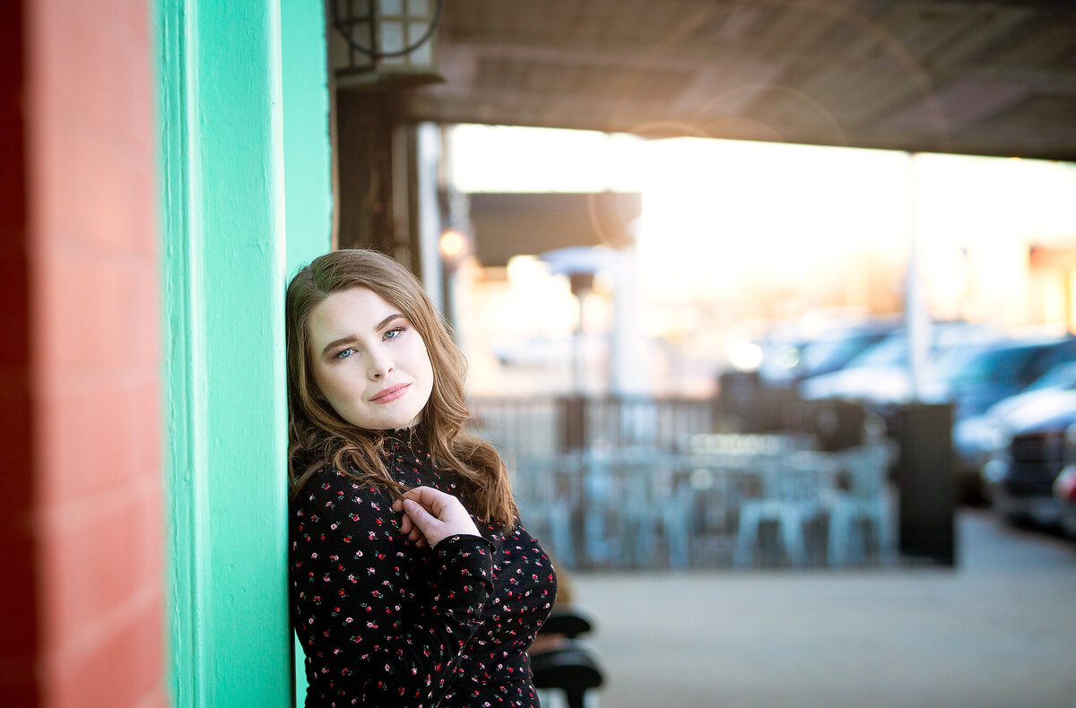 Senior girl leaning against green wall in canyon tx