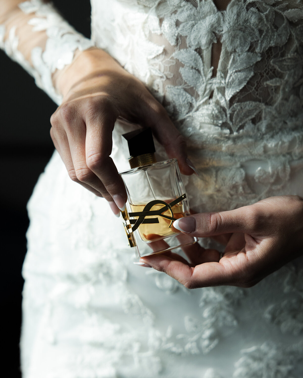 Mains de la mariée avec bouteille de parfum Yves Saint Laurent