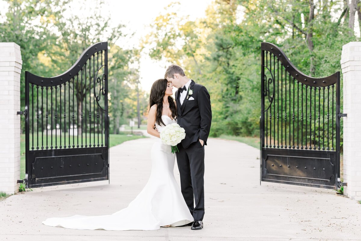 Arkansas wedding photographer image of s bride and groom stand in front of a gate outside the Venue at Oakdale.