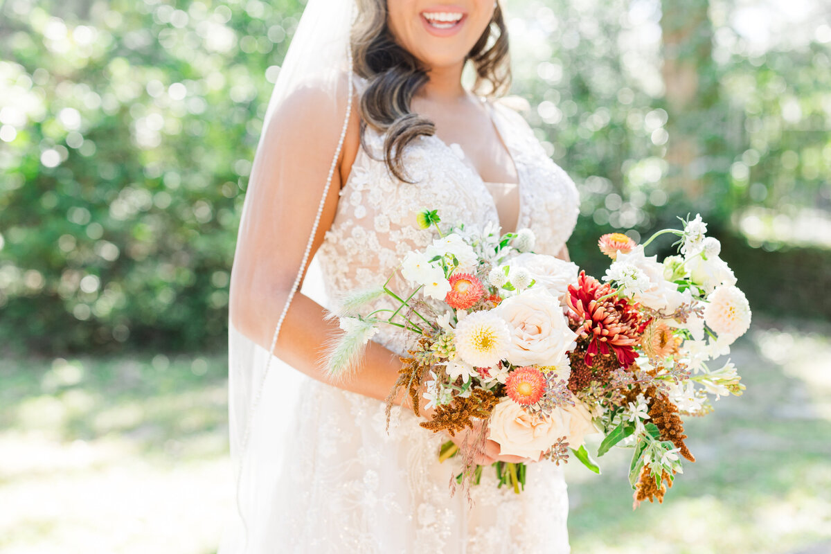 bride holding an orange, red, and white wedding bouquet
