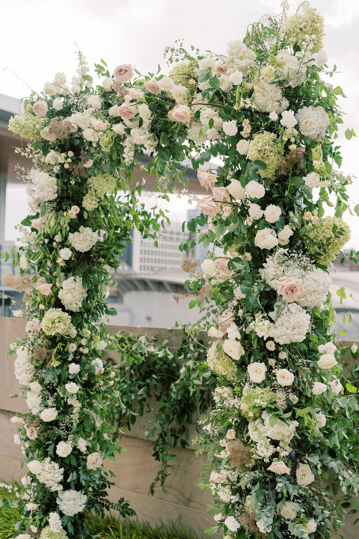 Oversized ceremony floral arch for summer wedding. Classic and timeless floral design in white, cream, taupe, champagne, and green. Lush ceremony florals for garden-inspired summer wedding. Florals composed of roses, hydrangea, baby’s breath, and organic greenery. Design by Rosemary & Finch Floral Design.