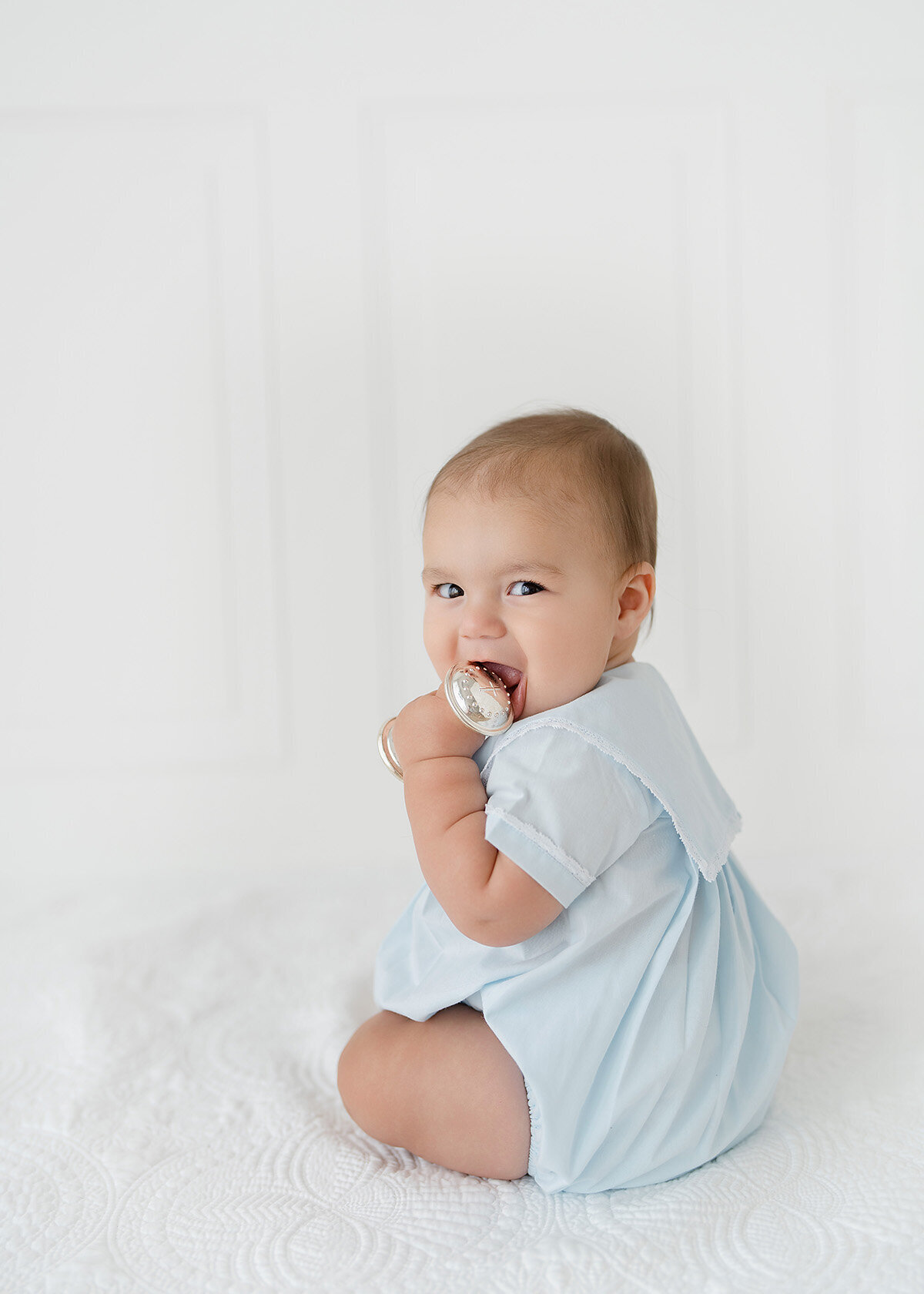 baby boy photographed wearing a grandmillenial style outfit with a silver rattle in a photo studio in st simons island