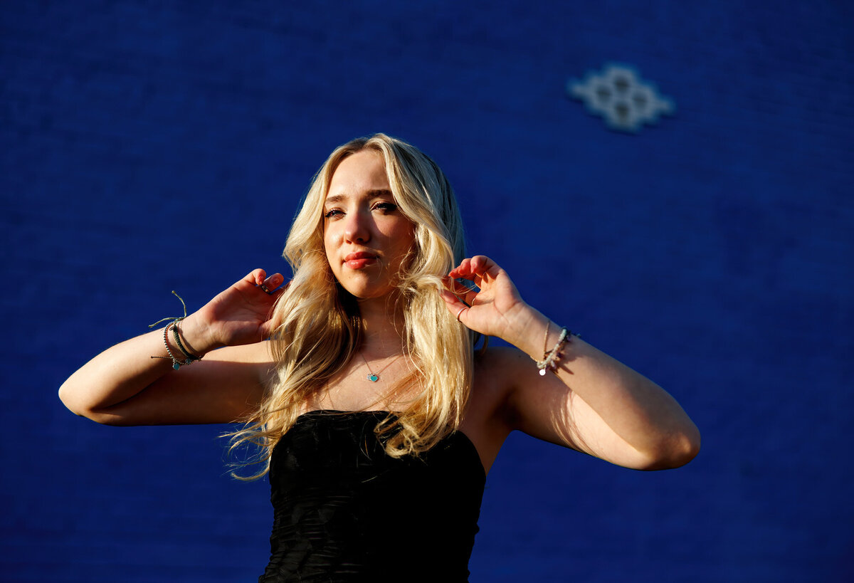 The sunlight lights up Maria with a blue brick wall behind her.
