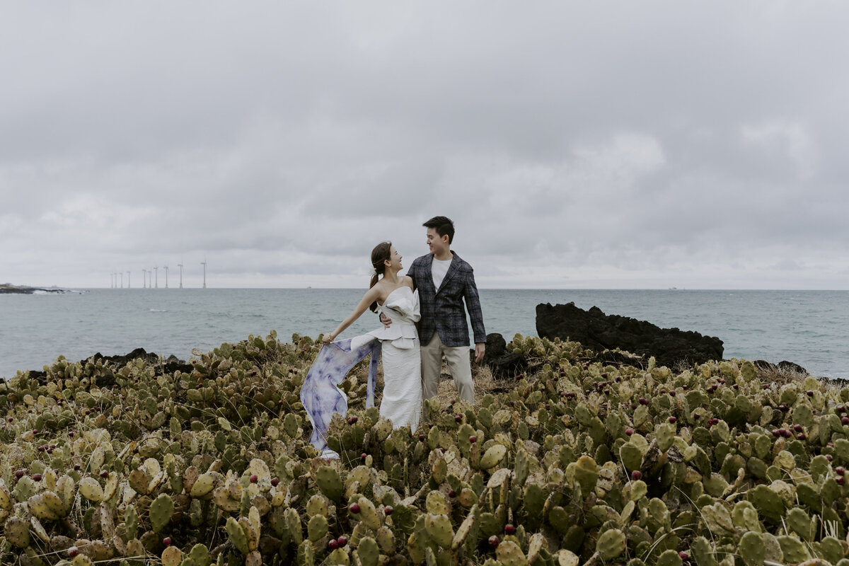 bride wearing a long white tube dress with violet design at the bottom while the groom wearing a checkered suit and a white inner with beige pants