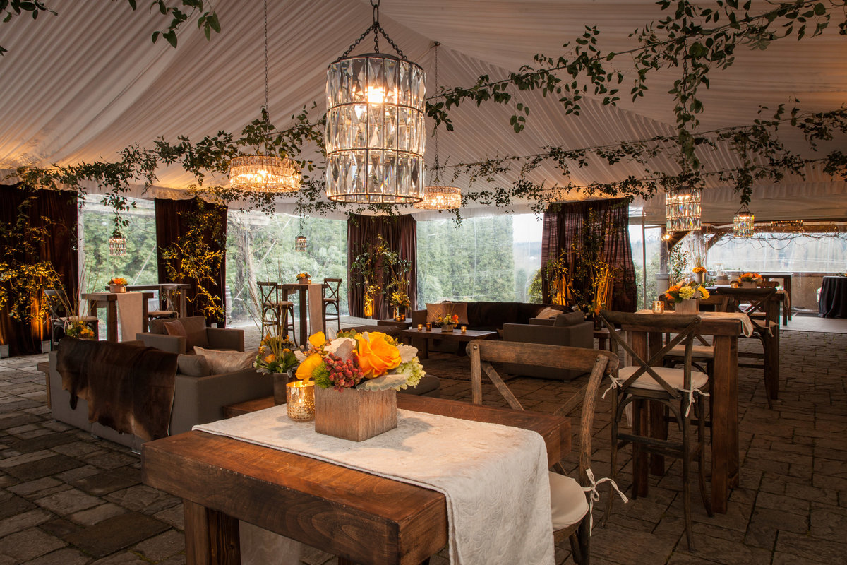 corporate party at Chateau Lill tent with ceiling greenery, lounge furniture, and yellow flowers, and brown draping, and crystal chandeliers