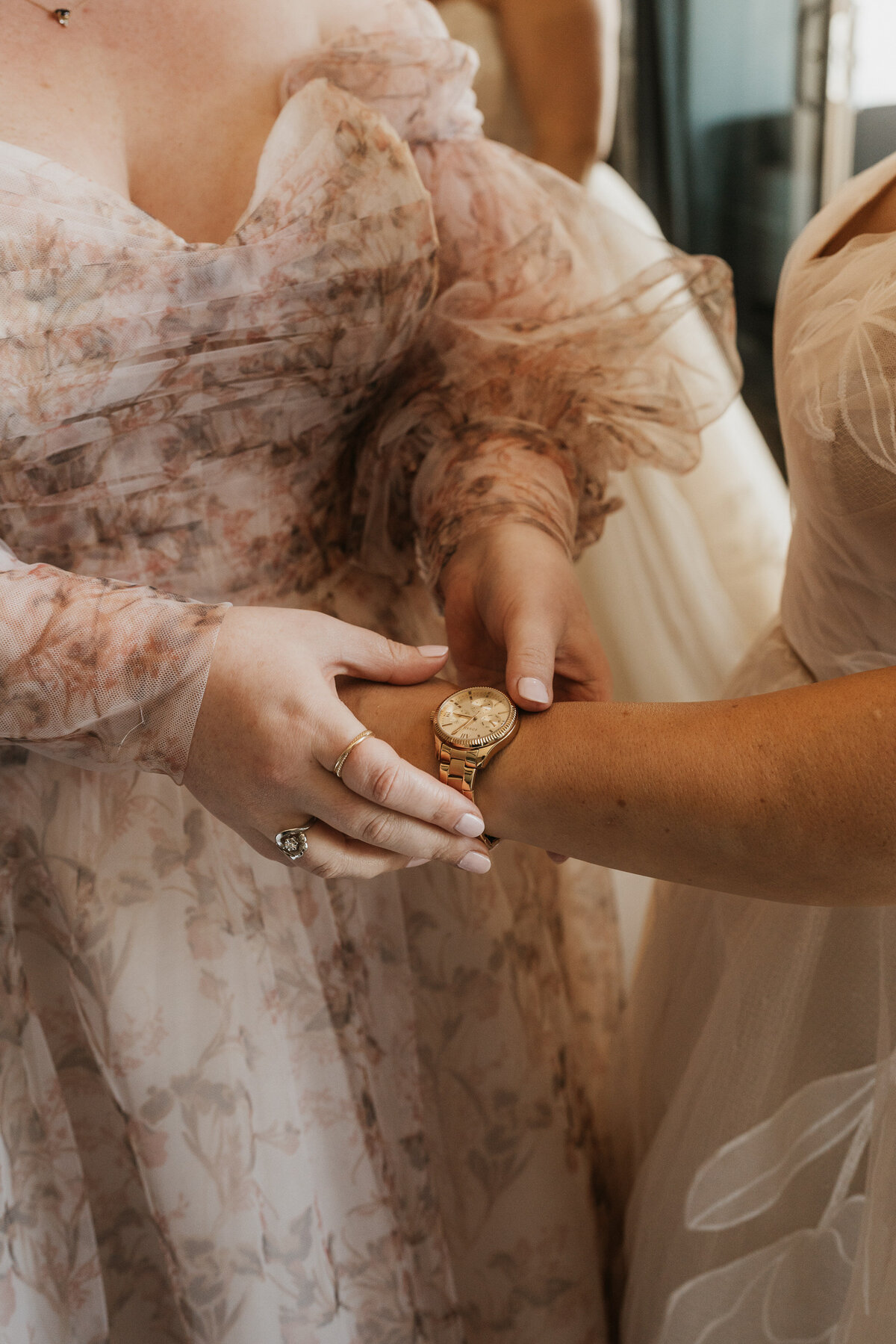 Someone holding another person's wrist as they help them put on a watch 