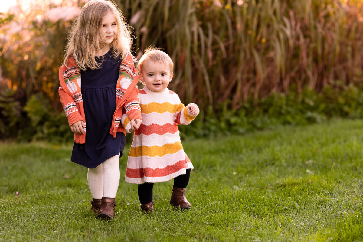Two young girls hold hands while walking by  Vermont Family Photographer