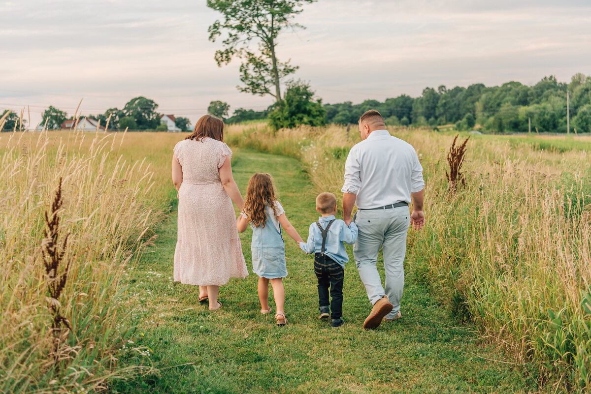 Family of four walking away from camera in field