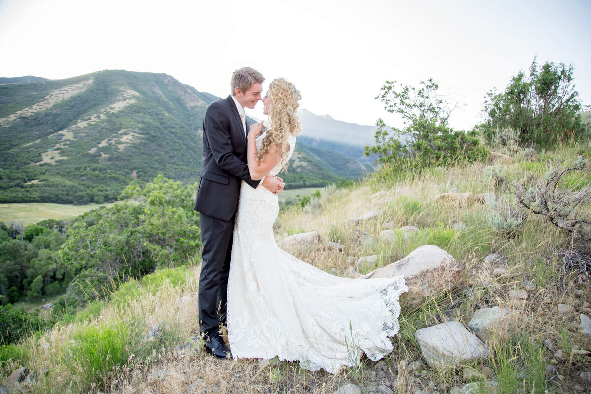 a wedding couple smiling at each other on a mountain