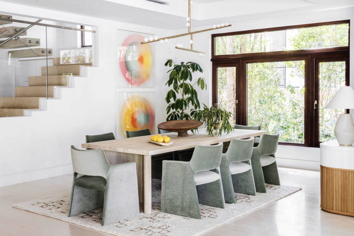 Dining room interior with light wooden table and green velvet upholstered chairs
