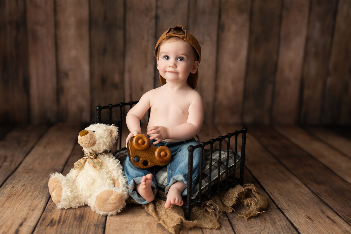 Rustic milestone photo of a baby boy with toy and teddy—styled with earthy tones and timeless textures.