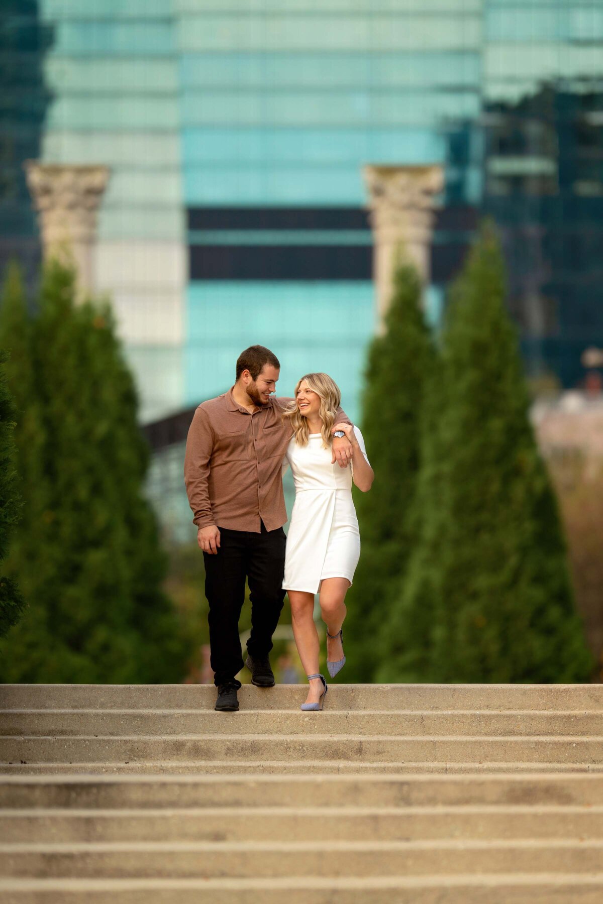 Young woman in white dress hugging her future husband and walking down the stairs