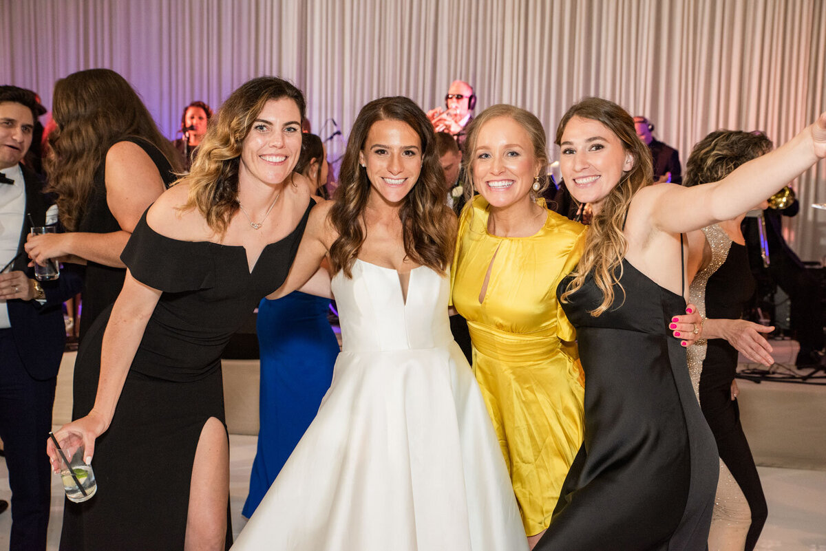A group of women posing for a picture with one wearing a yellow dress