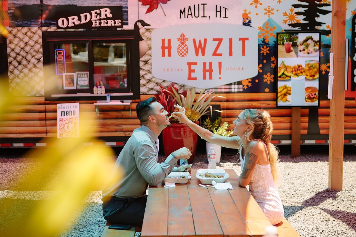 A bride and groom eat lunch at a food truck in Maui, Hawaii