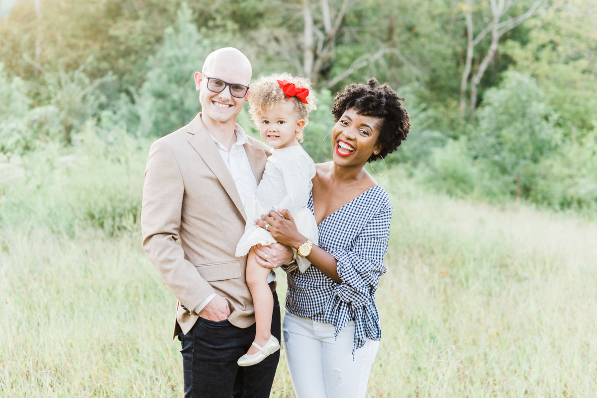 Mom and dad hold their daughter and smile for a family portrait in Raleigh NC. Photographed by Raleigh family photographer A.J. Dunlap Photography.