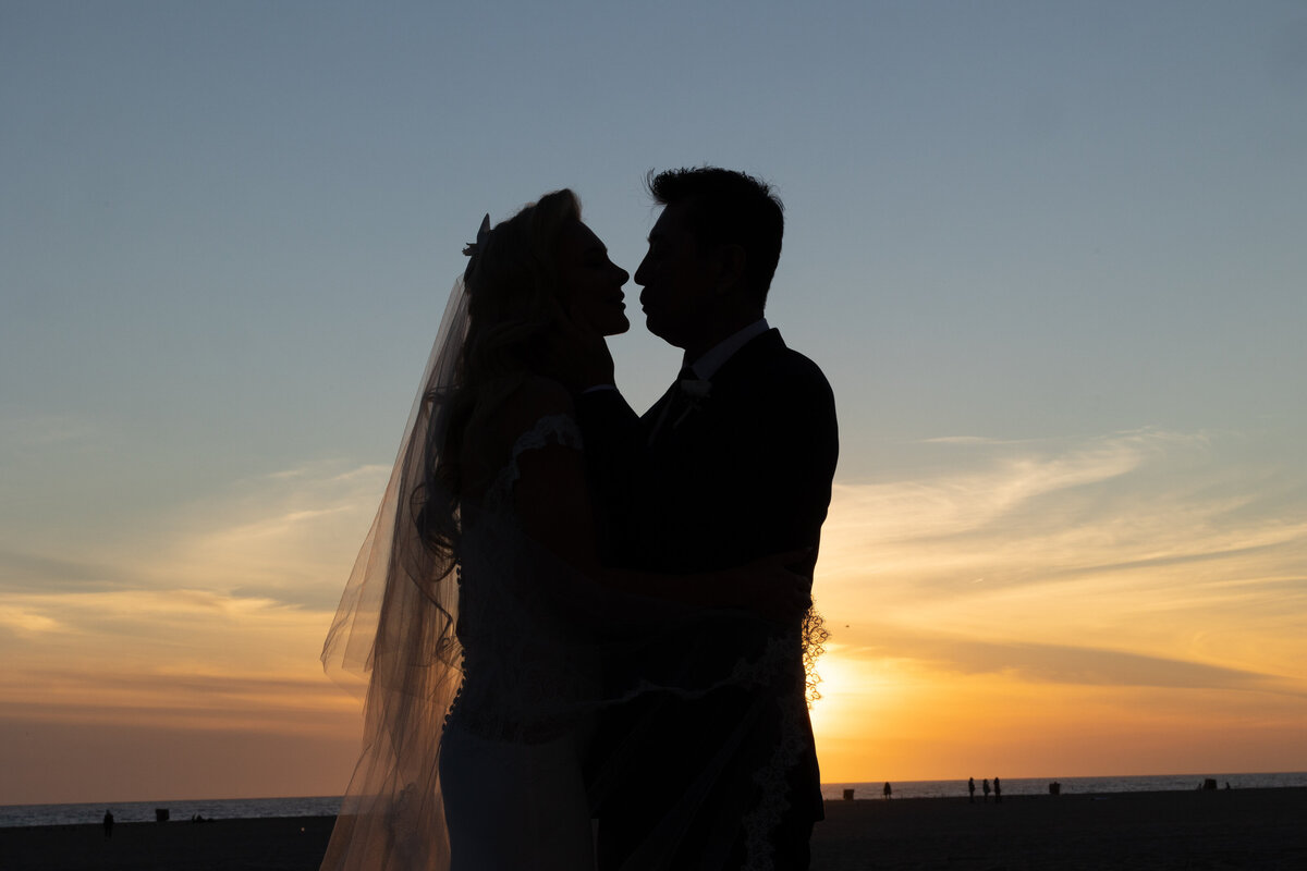 A bride and groom about to kiss at sunset