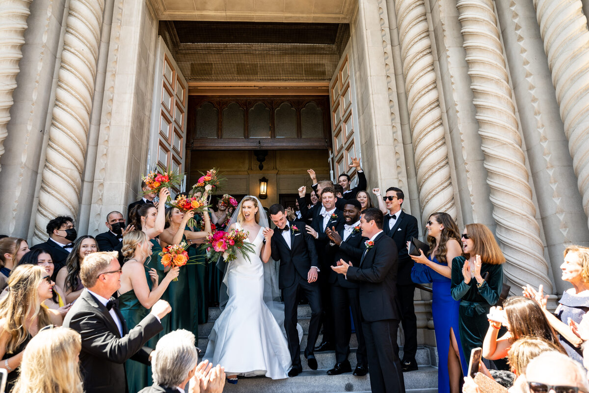 Professional Bay Area wedding photography featuring joyful couple and wedding party celebration at historic Saints Peter & Paul Cathedral in San Francisco