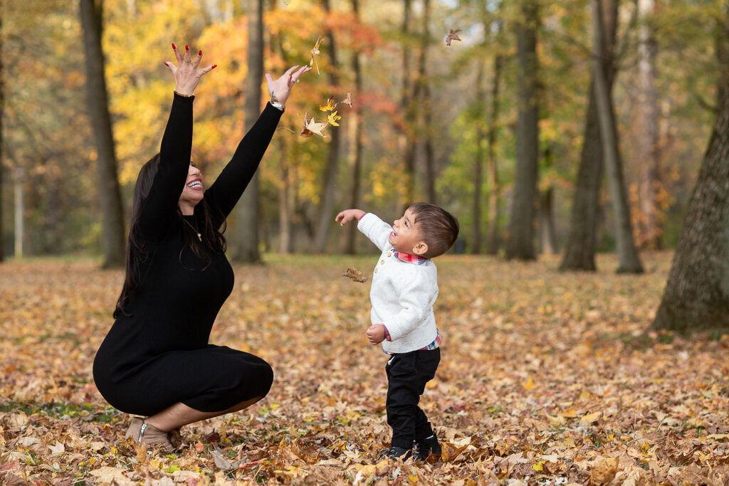 Mom plays in the leaves with son at Waterworks Park