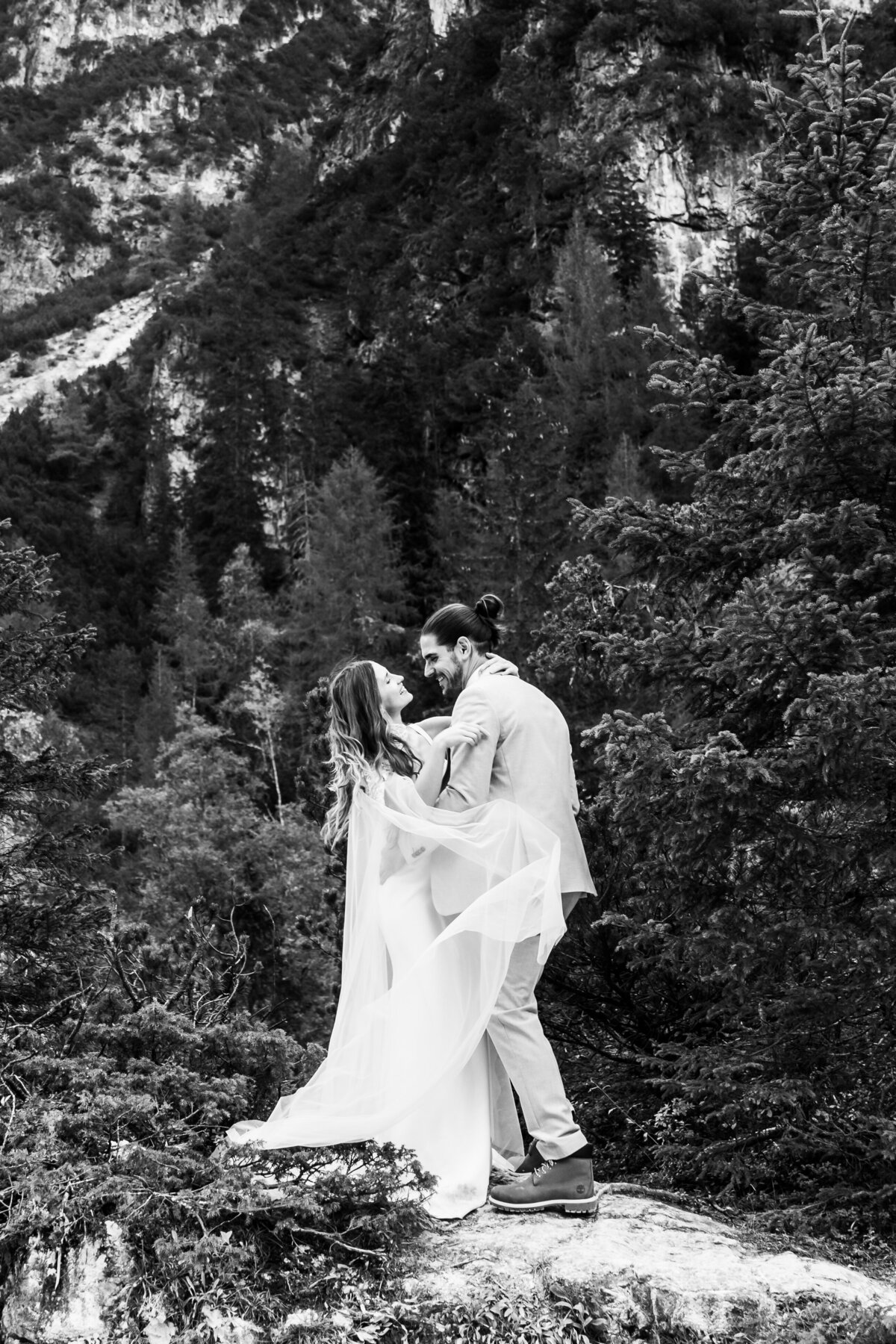 Elopement wedding couple posing on a cliffside with dramatic mountain views