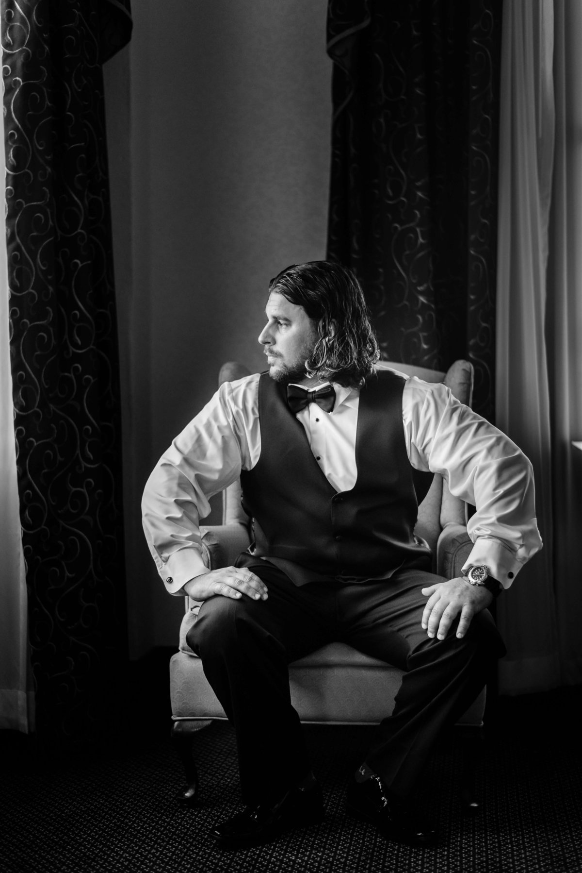 Groom sits nervously in a chair looking out a window before his wedding ceremony at the Floridan Palace Hotel in Downtown Tampa