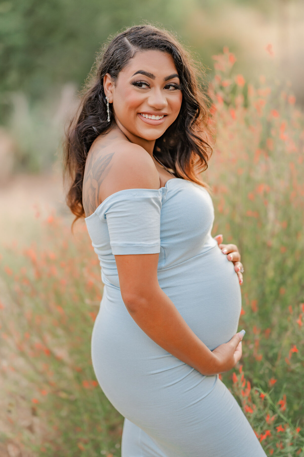 Expecting lady holds her belly and laughs over her should during photos with San Antonio maternity photographer Cassey Golden.
