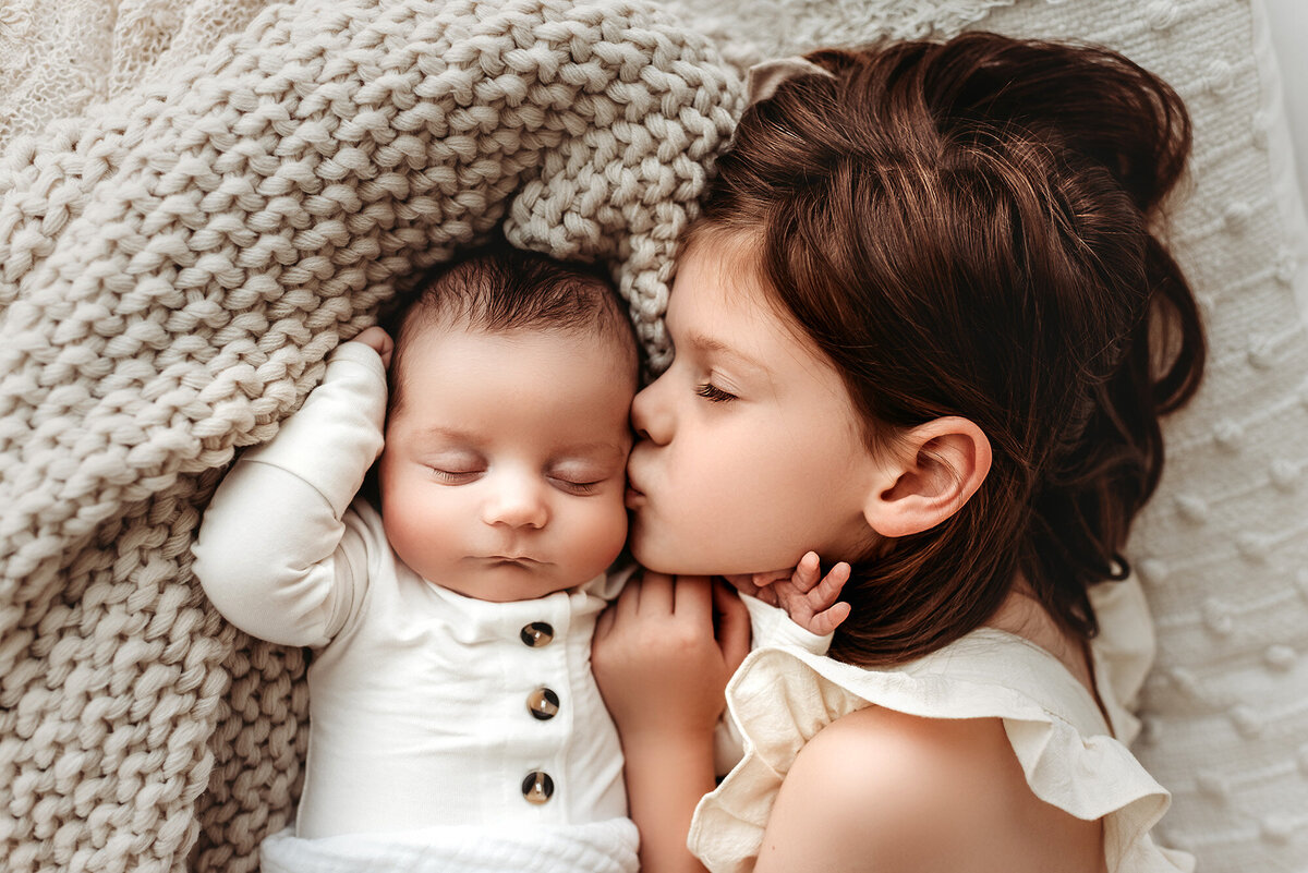 big sister kissing newborn brother by Alyssum, Denver photographer
