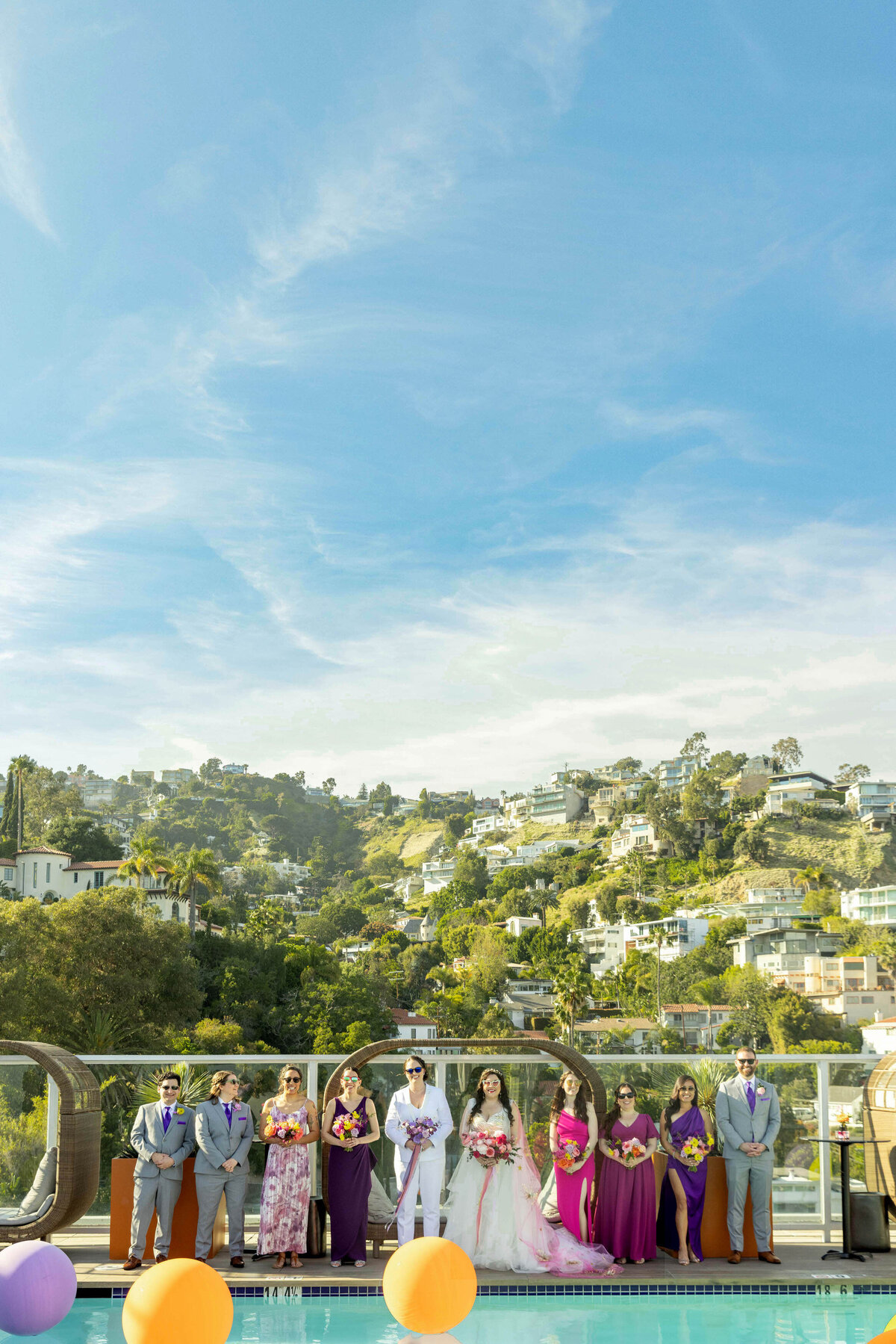 View of a wedding party and brides from across a pool.