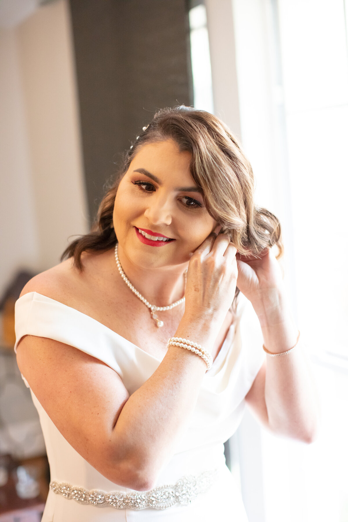bride wearinputting on earrings at Gardens of West Green by photographer in San Antonio Firefly Photography
