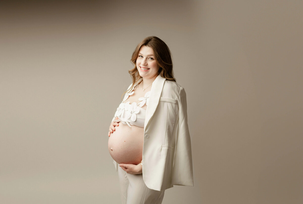 Standing maternity portrait with cream  blazer and floral bra in Maple Grove 